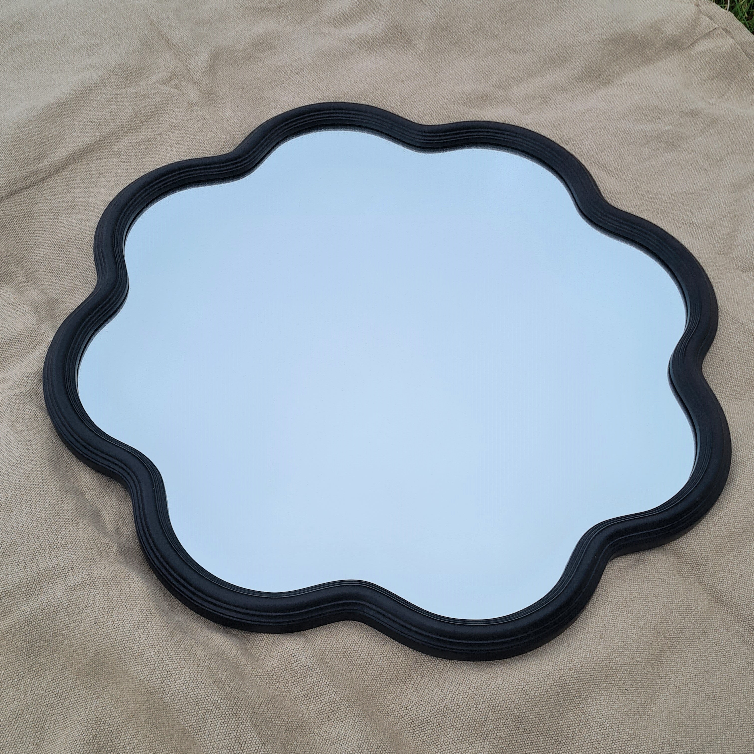 Black framed large mirror with scalloped edges.